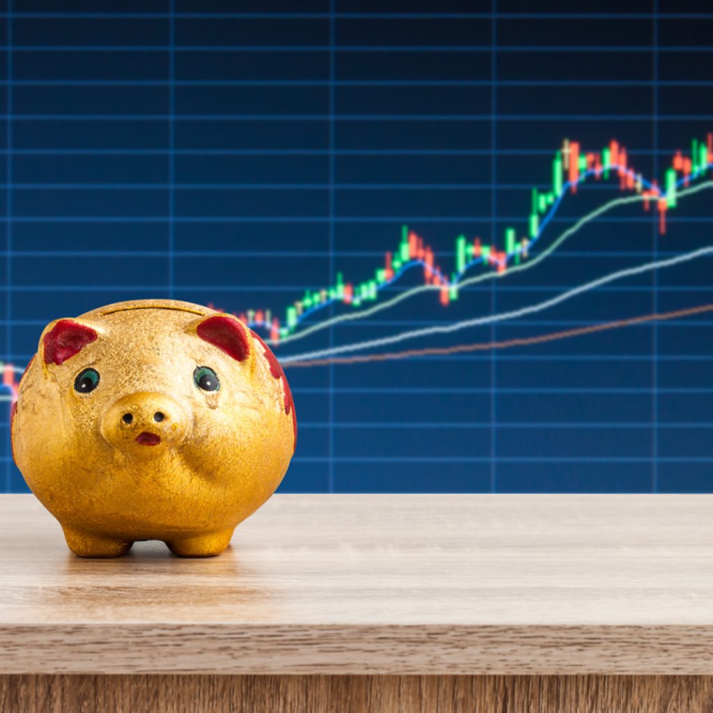 a piggybank in front of a stock market chart